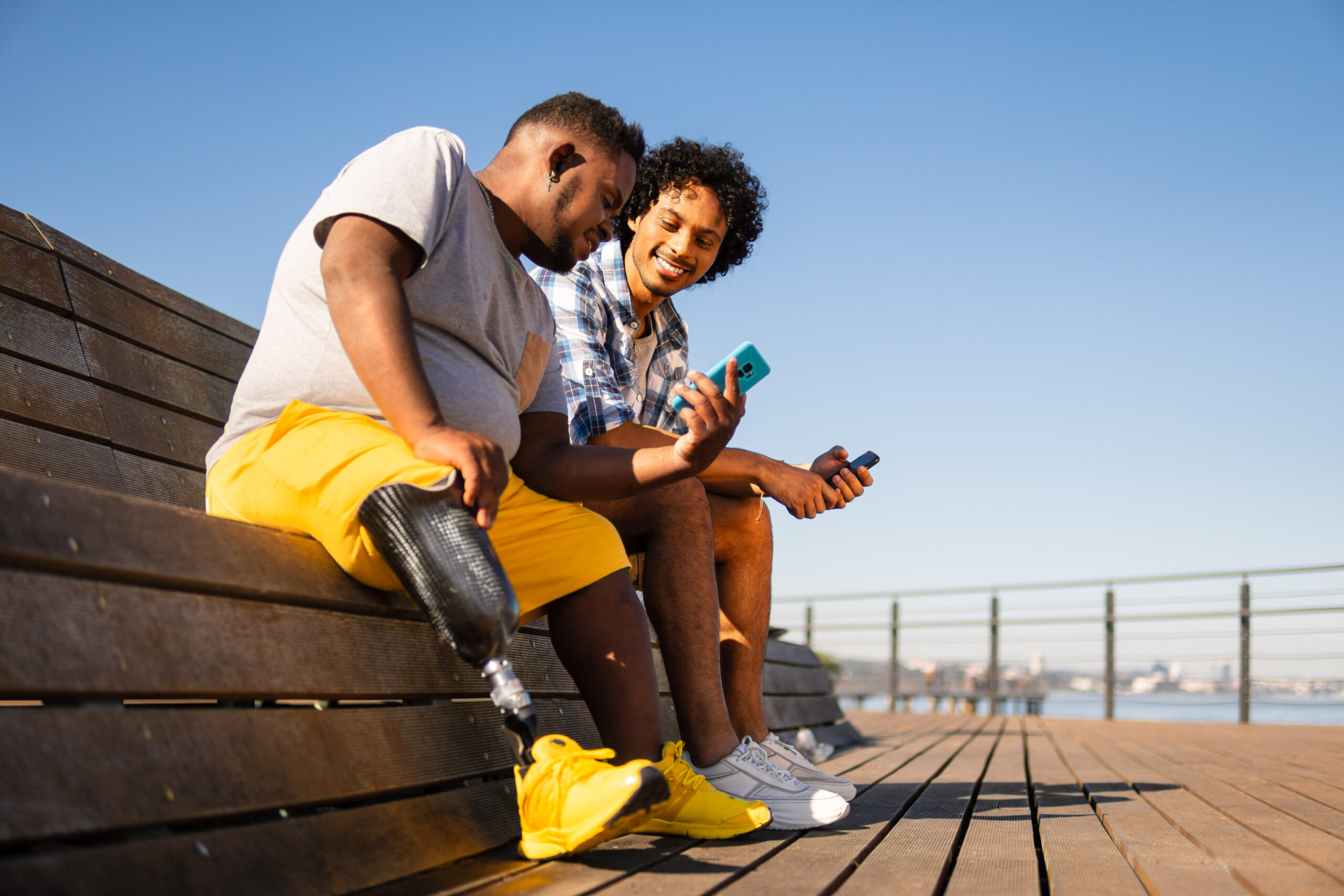 disabled black man showing mobile screen to friend