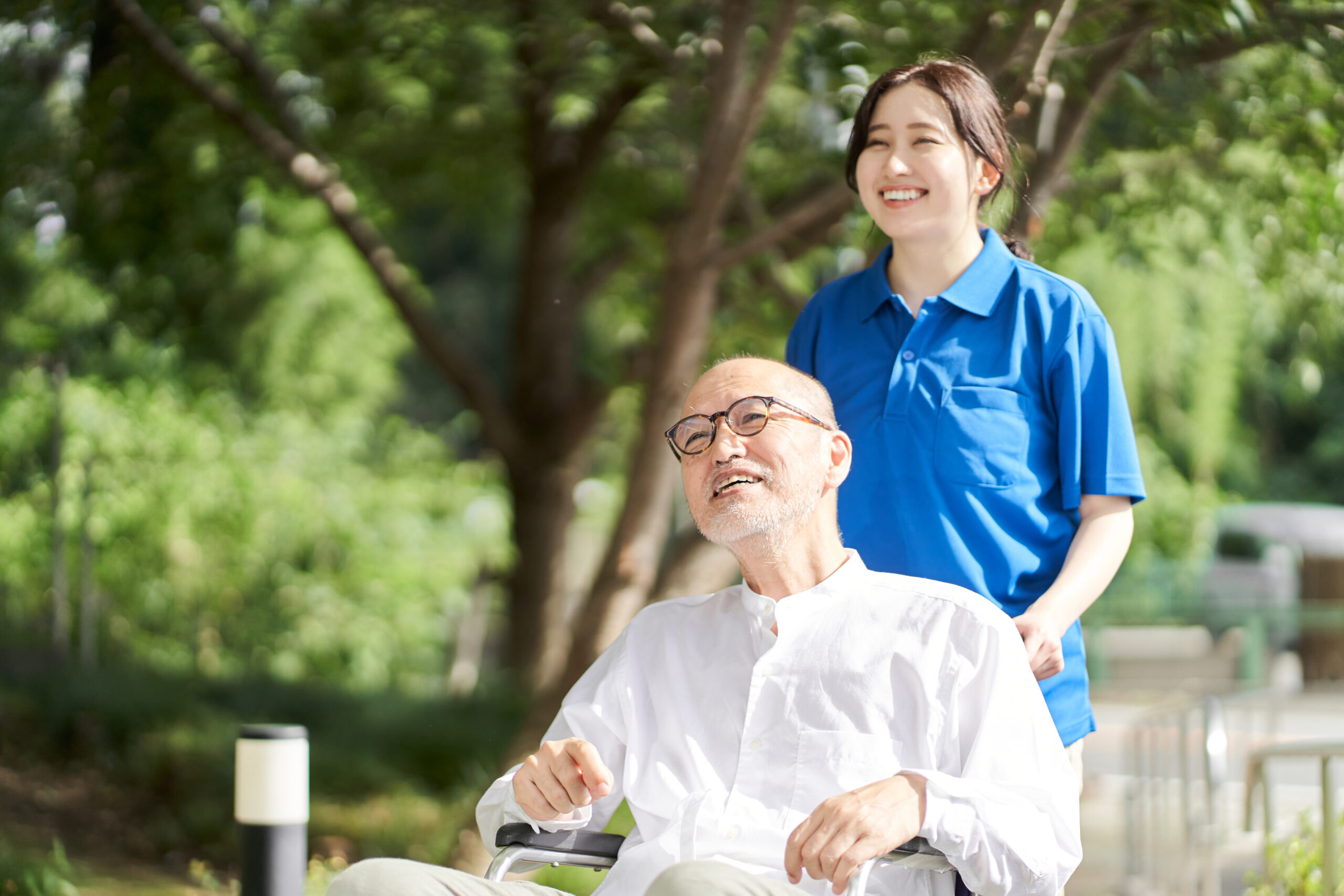 Female caregiver supporting an aging man in a wheelchair